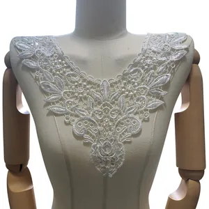 Detalle de aplique de encaje floral con lentejuelas blancas en un torso de maniquí.