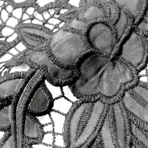 Macrobeeld van zwart wateroplosbaar kantborduurwerk met verfijnde bloemmotieven