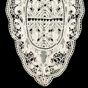 Detailed macro shot of white cotton embroidered lace collar with hollow-out pattern