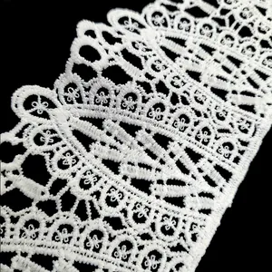 Macro detail of white milk silk embroidered lace trim with hollow out floral pattern
