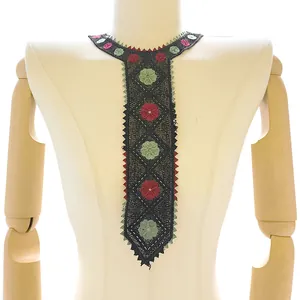 Close-up of a black lace neck applique with red and green floral embroidery