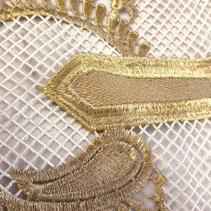 Close-up of intricate gold embroidery on white lace mesh fabric trim.