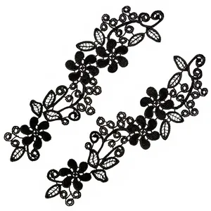 Vue détaillée de patchs de fleurs en dentelle noire symétrique avec texture de broderie 3D.