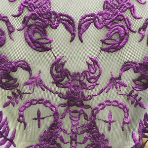 Close-up macro shot showing detailed purple embroidery on delicate mesh lace fabric