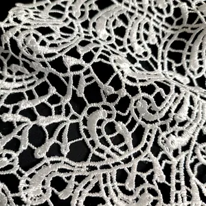 Macro detail of white water-soluble lace embroidery with intricate floral patterns