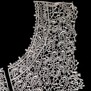 Macro view of white water-soluble lace faux collar with intricate embroidered floral patterns