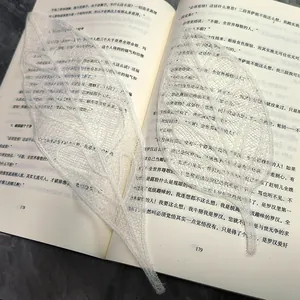 Κοντινό πλάνο από λεπτεπίλεπτα λευκά δαντελένια κεντήματα σε σχήμα φύλλου σε βιβλίο