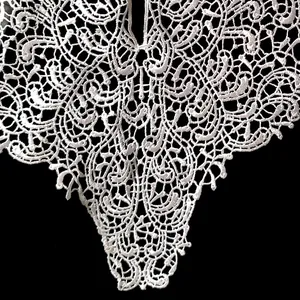 Close-up of intricate white water-soluble lace embroidery pattern for neckline decoration