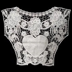 Dettaglio del colletto in pizzo bianco con ricami di fiori e motivo a cuore