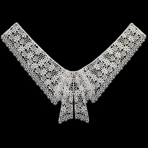 Detail of white water-soluble lace floral collar with intricate embroidery on black background
