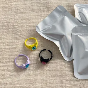 Close-up of cute monster opening rings in yellow, purple, and black with eye details