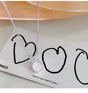 Primo piano di una collana in argento con pendente tondo in agata bianca e fiocco.