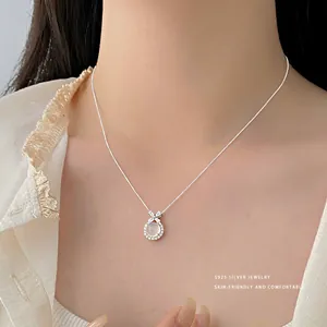Primo piano di una collana in argento S925 con ciondolo in agata bianca su modella.