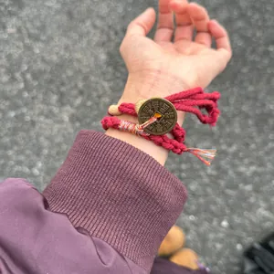 Close-up detail of a handmade red woven ethnic bracelet with vintage mountain ghost coin