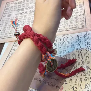 Detail of handmade red braided bracelet with traditional Chinese coin charm on wrist