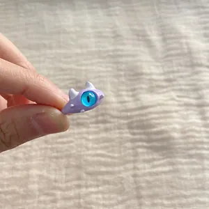 Close-up of cute purple monster ring with big blue eye on fabric background