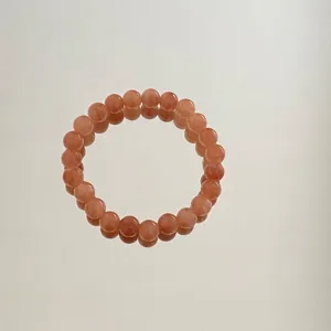 Detailansicht eines Perlenarmbands aus Pfirsich-Aventurin-Jade mit Spiegelreflexion