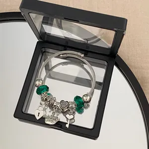 Detail of silver charm bracelet with heart crown charms and green beads in box