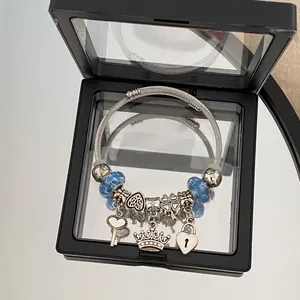 Silver charm bracelet with blue beads, heart key and crown charms in display box