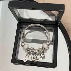 Detailed view of silver charm bracelet with heart, crown, and key pendants in a display box.