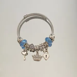 Macro view of a silver cable bracelet with blue beads and a crown charm