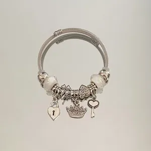 Detail view of silver-toned charm bracelet with heart, crown, and key pendants.