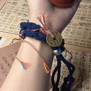 Close-up view of a hand-woven blue braided bracelet with a traditional coin charm.