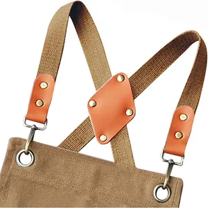 Detail shot of heavy canvas apron with cross-back straps, leather patch, and metal hardware.