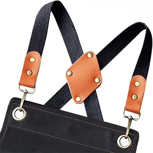 Adjustable cross back apron detail with durable canvas, leather reinforcement, and metal rings.