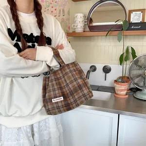 Detail view of the brown plaid woolen handbag, showing the textured fabric and casual design.