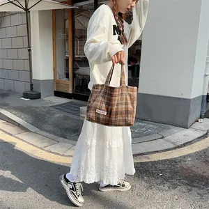 Detailed shot of brown plaid wool tote bag showing texture and street style context.