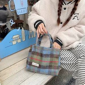 Plaid wool handbag detail showing the classic blue and green check pattern and fabric texture.