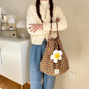 Vue rapprochée d'un sac seau élégant à carreaux avec charmante peluche florale, gros plan.