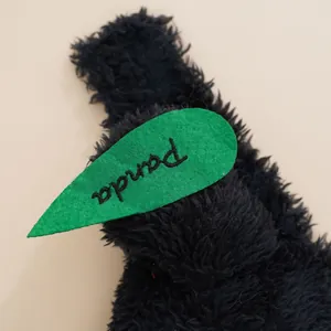 Black plush pet costume detail showing soft furry texture and cute green leaf decoration with text.