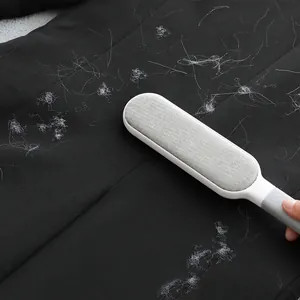 Portable static lint remover brush efficiently cleaning white pet hair off black clothes.