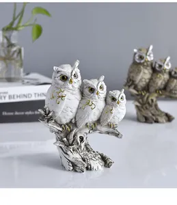 Detailed view of three white resin owl figurines on a tree branch home decor ornament