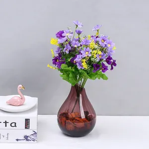 Dettaglio mazzo di margherite artificiali, fiori finti in plastica viola in vaso di vetro per decoro.