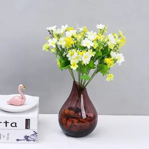 Bouquet di piccole margherite artificiali con vaso in vetro per decorazione tavola casa.