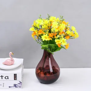 Dettagli ravvicinati di fiori artificiali in plastica di margherita in vaso di vetro viola.