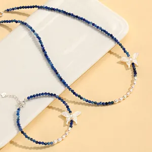 Detail view of blue crystal and freshwater pearl jewelry set with butterfly charms