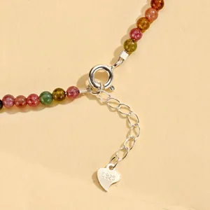 Macro detail of multi-color crystal jewelry with S925 silver heart tag and extension chain