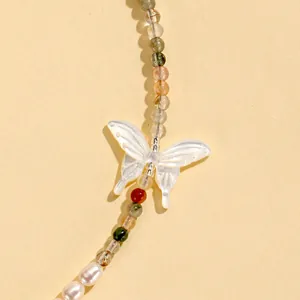 Close-up detail of an elegant white shell butterfly pendant with natural crystal beads and pearls.