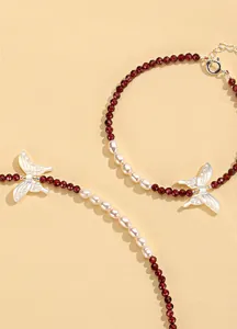 Detail of a red crystal and pearl jewelry set featuring elegant butterfly charms.
