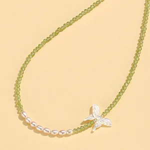 Detailed view of freshwater pearls and green crystal beads with a butterfly charm.