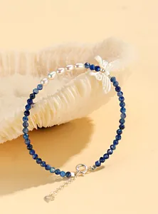 Detailed macro view of handcrafted blue crystal bracelet with elegant pearl and butterfly charm