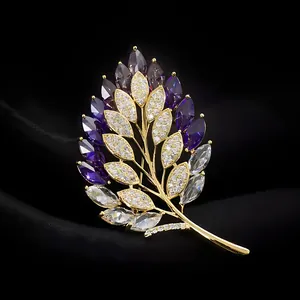Detailed shot of exquisite gold wheat leaf brooch with purple and clear cubic zirconia stones.