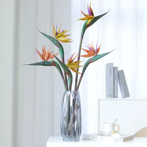 Large artificial bird of paradise flowers in grey glass vase for home living room decor.