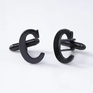 Close-up detail shot of black letter C cufflinks, perfect for formal french shirts.
