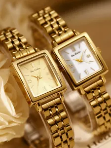 Detailed macro shot of two vintage square gold stainless steel women's watches with luxury finish