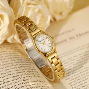 Détail d'une élégante montre femme dorée avec cadran ovale sur un livre ancien